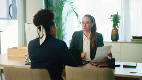 zwei frauen sitzen während eines jobinterviews an einem schreibtisch