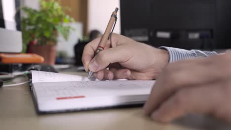 man in an office handwriting, planning hes schedule