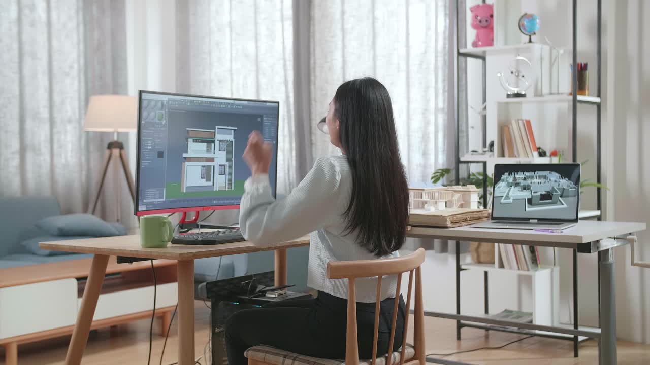 アジアの女性エンジニアがデスクトップで家をデザインしながら祝います サイバーゲーム 家のデザインと装飾