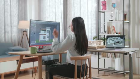 asian woman engineer celebrating while designing house on a desktop at home. cyber games house design and decoration