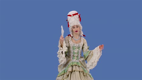 portrait of courtier lady in white vintage lace dress and wig is waving a fan. young woman posing in studio with blue screen background. slow motion