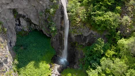 Flying-down-near-a-tall-waterfall-in-the-mountains-untouched-by-humans