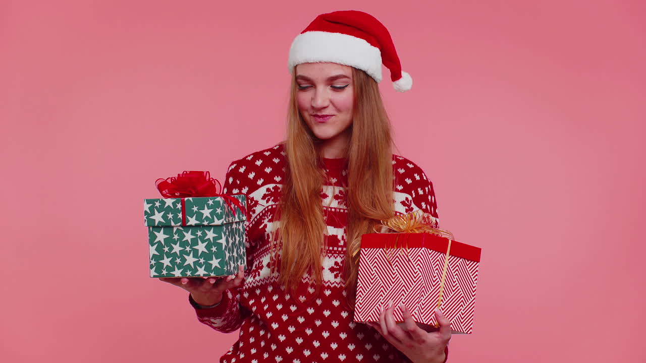 mujer con suéter rojo de navidad sombrero de papá noel, sonriendo, sosteniendo dos cajas de regalos compras de regalos de año nuevo