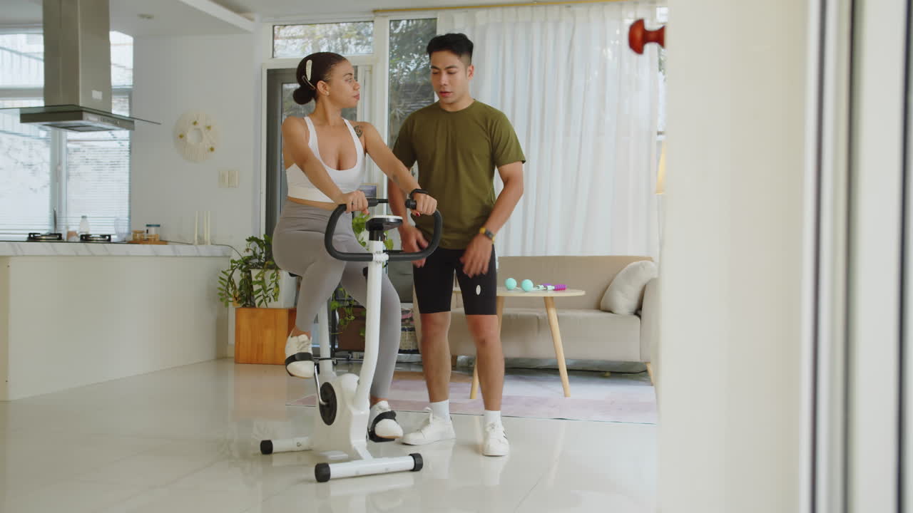 Coach Assisting Female Client Training on Fitness Bike