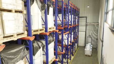 a warehouse shelf laden with neatly stacked pallets, heavy white bags placed on top