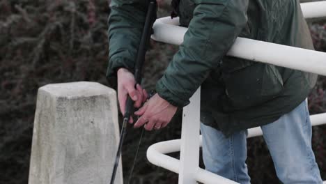 a fisherman is spinning his fishing reel at the side of an bridge while streetfishing