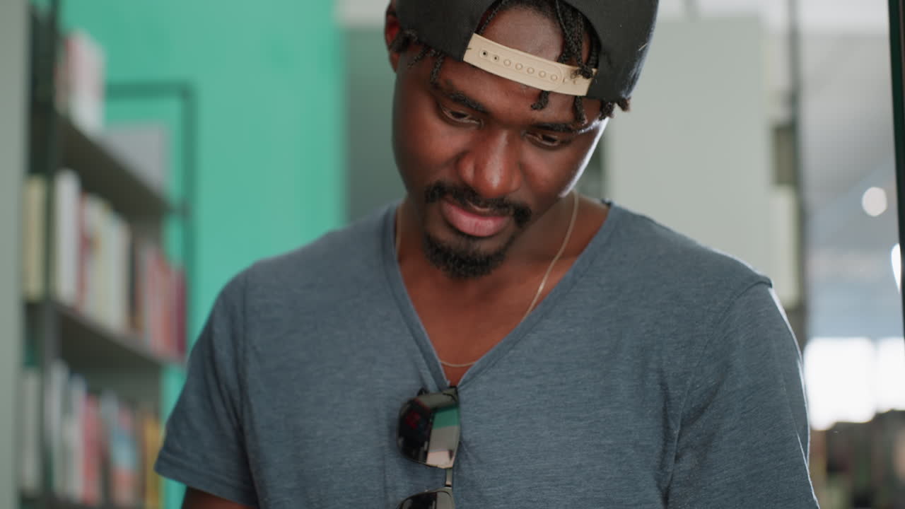Close up of man wearing casual t shirt holding open book while smiling with head slightly bowed, focusing on pages with bright light softly shining from behind