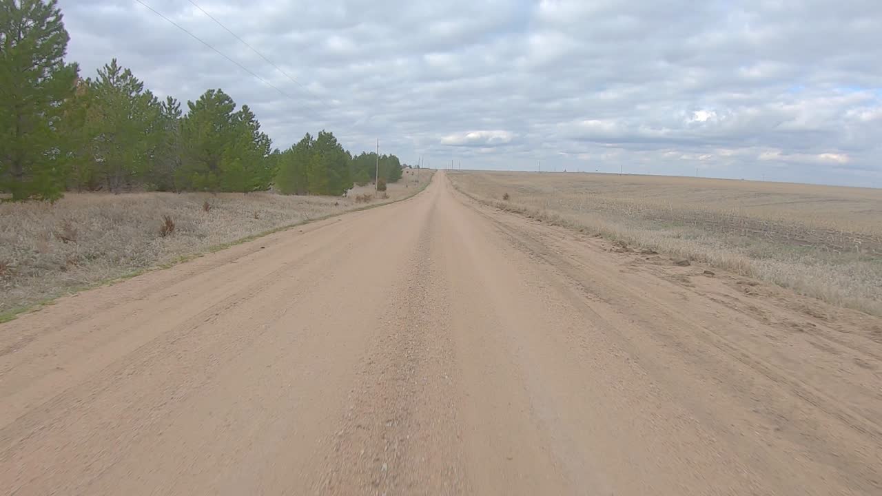 punto de vista conduciendo en un tramo recto de camino de ripio en la zona rural de nebraska en un día nublado de invierno