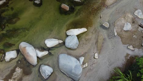 Water-flows-calmy-through-rocky-river-bed,-top-down-aerial