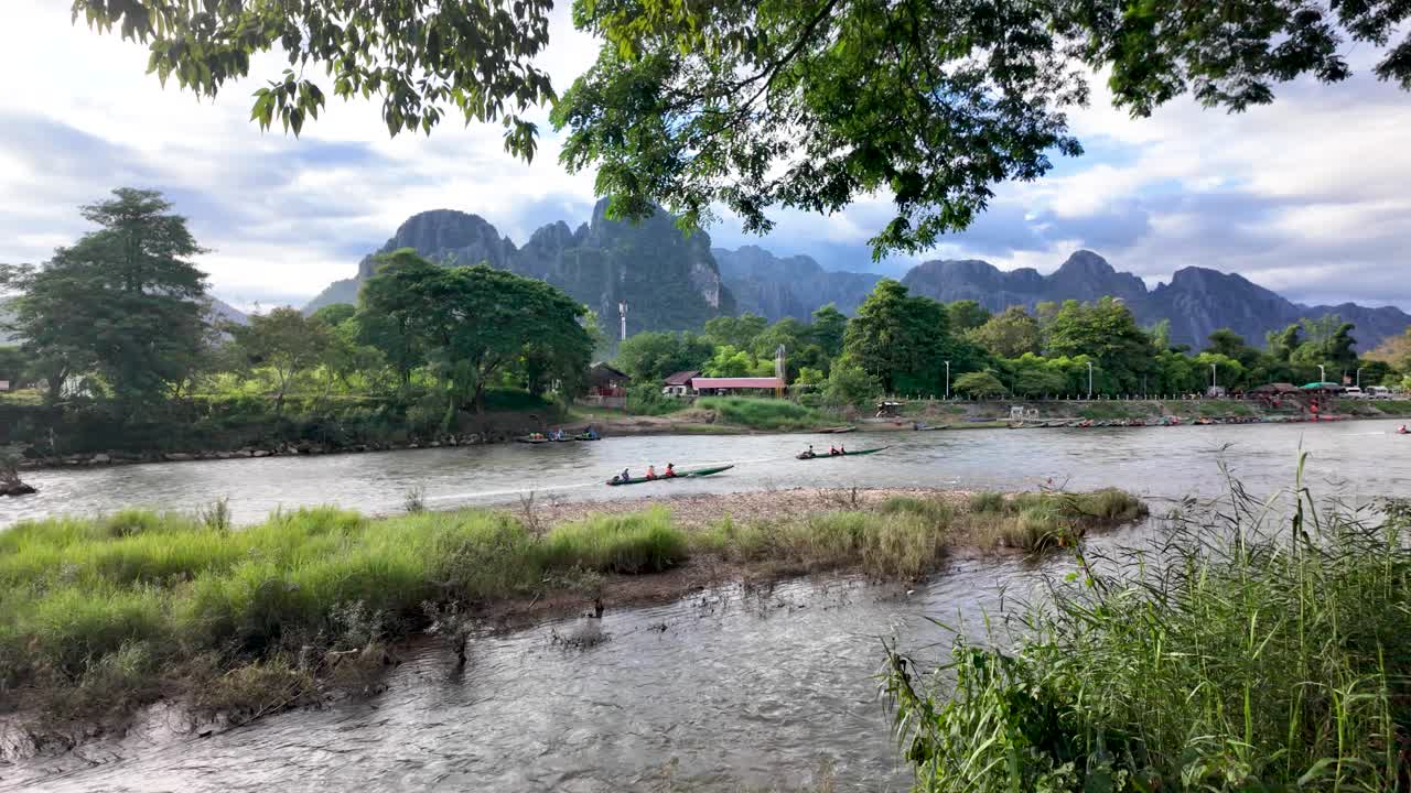 Longtail boats navigate the Nam Song River with limestone karsts in the background