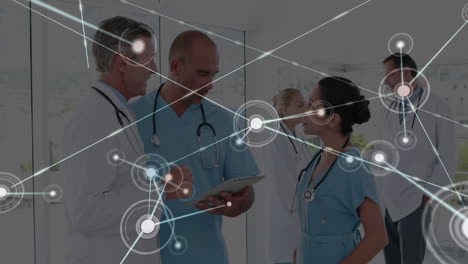 animation of dots connected with lines over multiracial doctors discussing over digital tablet