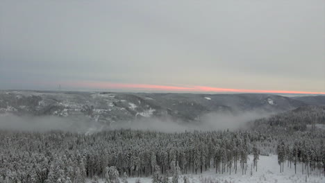 paisaje rural de invierno con valle brumoso, puesta de sol en segundo plano