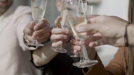 close-up shot of peoples hands clinking glasses of champagne