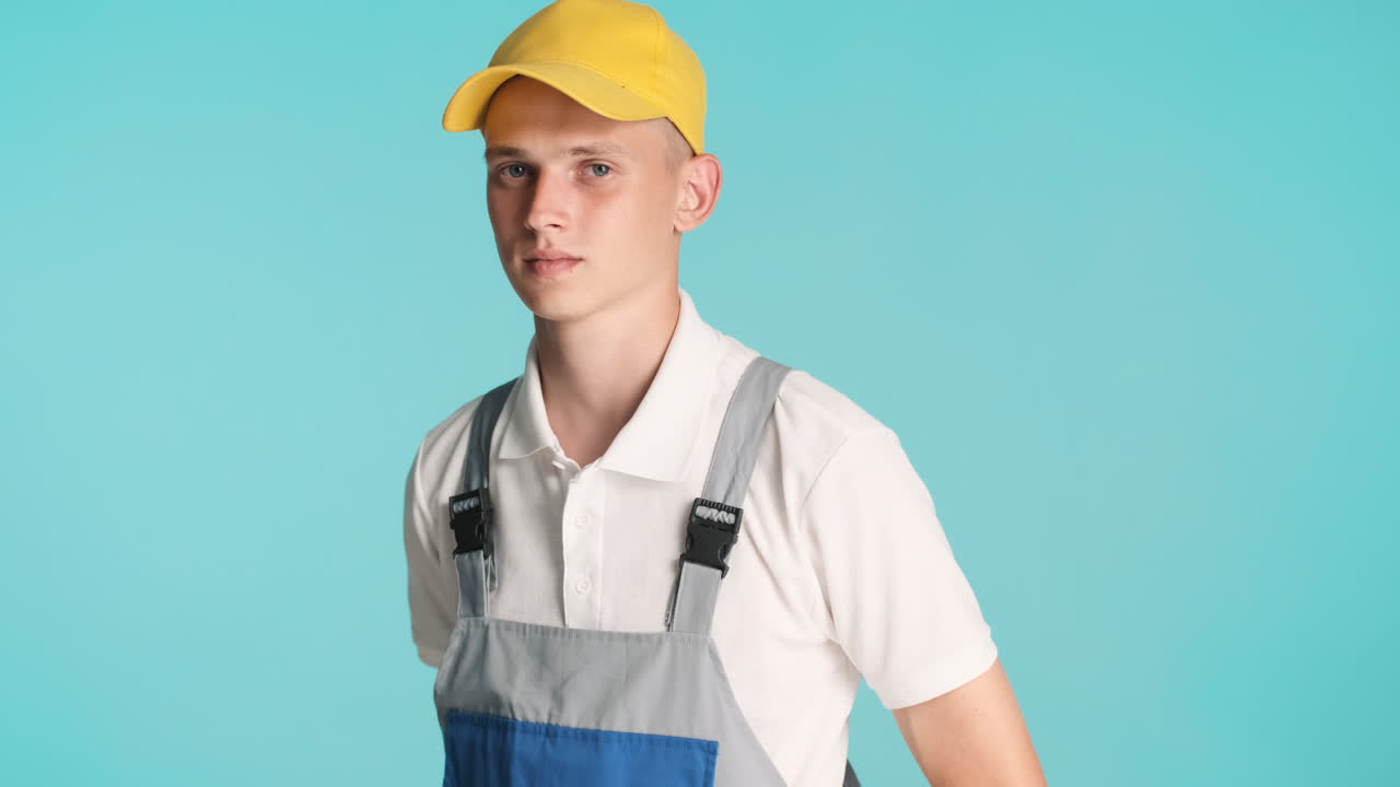 노란 모자를 입은 금발 건축가가 포즈를 취하고 있습니다.