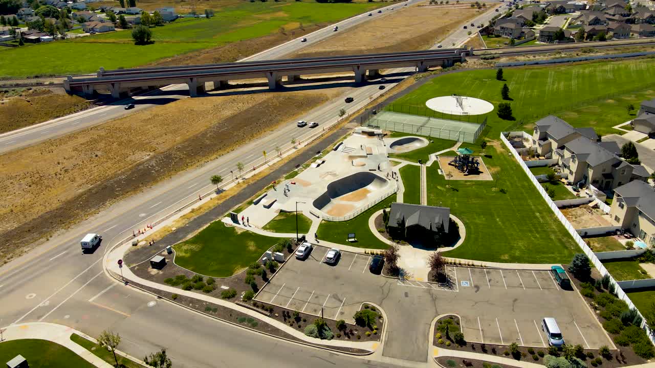 vista aérea en órbita de un parque de patinaje entre una autopista y un barrio suburbano