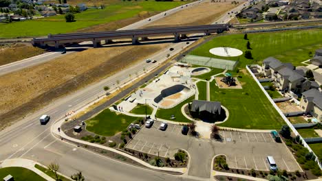 vista aérea en órbita de un parque de patinaje entre una autopista y un barrio suburbano