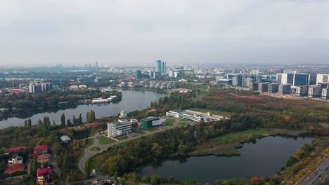 aerial view of bucharest suburbs with lake, autumn foliage, and modern buildings