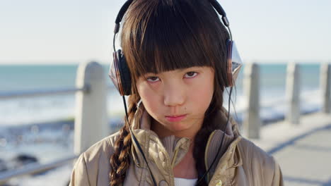 Sad,-headphones-and-face-of-Asian-girl-by-ocean