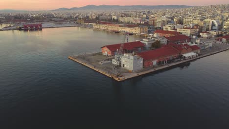 Amanecer-Frente-Al-Mar-En-Tesalónica:-Un-Dron-Aéreo-Captura-La-Primera-Luz-En-El-Emblemático-Muelle,-Iluminando-El-Sereno-Mar-Egeo:-Los-Vibrantes-Colores-De-La-Mañana-Pintan-El-Paisaje-Urbano-Costero-De-Grecia-Θεσσαλονίκη,-Ελλάδ?