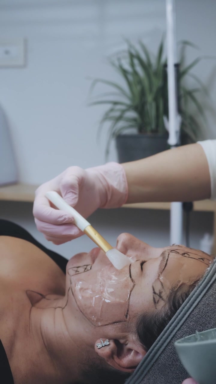 Cosmetologo che applica del gel sul viso di una paziente per un trattamento estetico.