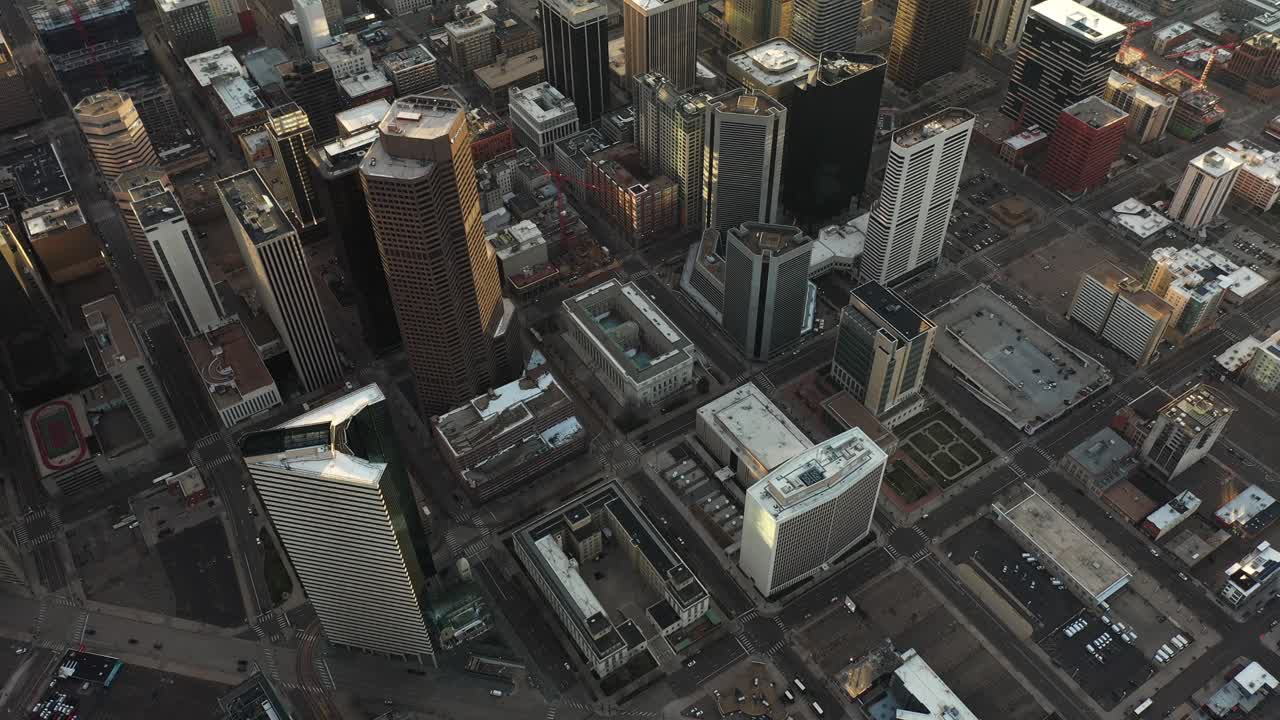 Luftfoto af Downtown Denver, det centrale finansdistrikt, med moderne skyskrabere i solnedgangens skær, en afslørende tilt-up droneoptagelse.