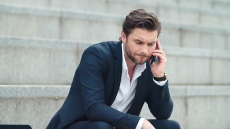 Business-man-talking-on-cellphone-at-street.-Worried-businessman-using-phone