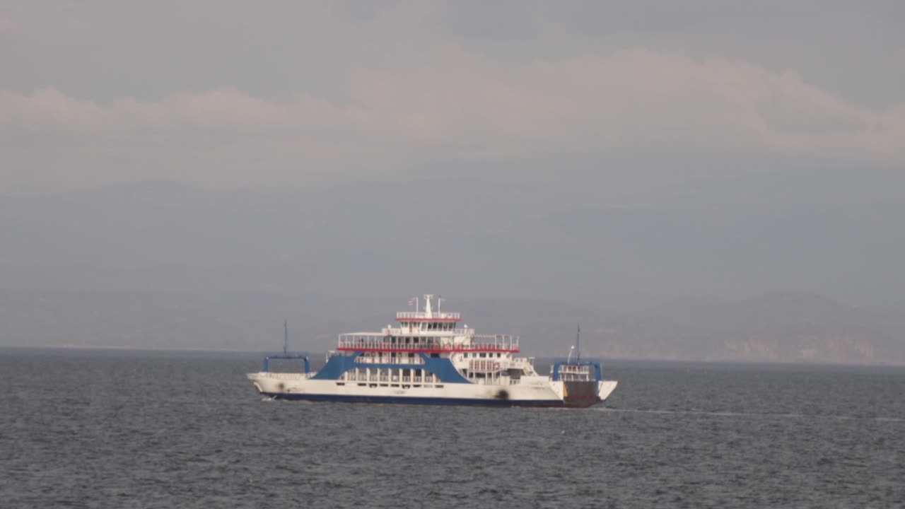 ferry blanco y azul transportando pasajeros, carga y vehículos, a través del océano pacífico en un día soleado en el golfo de nicoya, costa rica