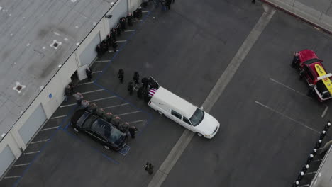 Dron-Aéreo-Sobre-Coche-Fúnebre-Blanco-Mientras-La-Gente-Carga-El-Ataúd-Fuera-Del-Coche-Fúnebre-Blanco