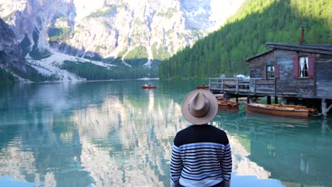 man with a hat turns back and smiles in lago di braies in dolomites, italy