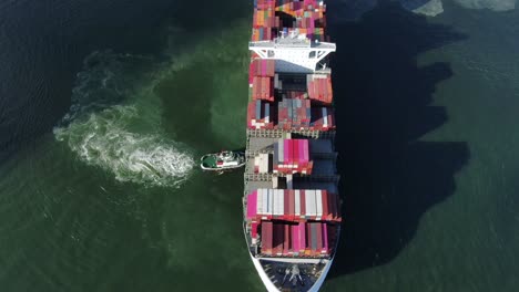 dos remolcadores que maniobran un gran buque portacontenedores vacío en el puerto de hong kong, vista aérea