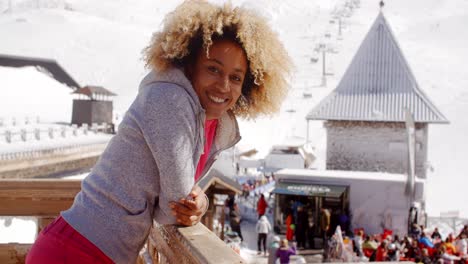 smiling woman leaning on railing at ski resort