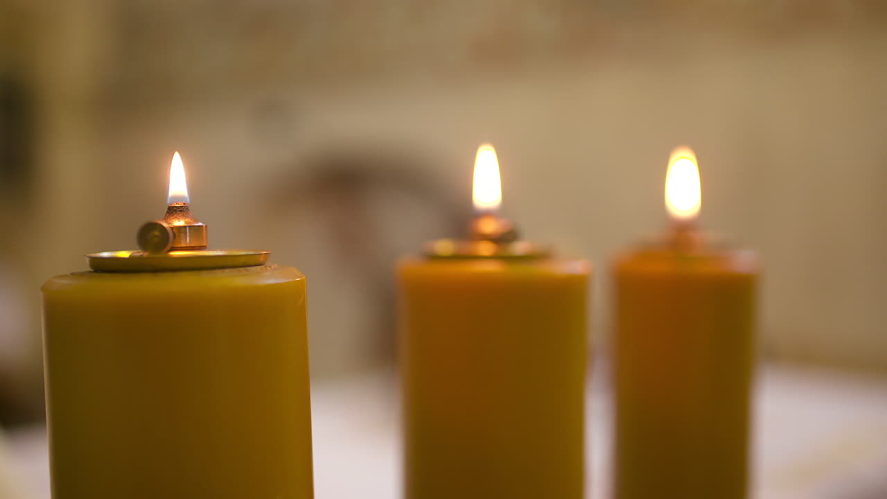 Fiamme tremolanti su tre candele gialle a fuoco morbido
