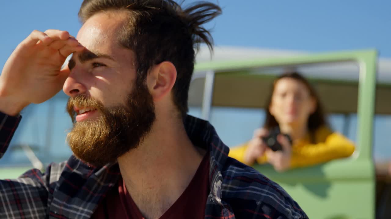 젊은 남자가  ⁇ 은 날 4k에 그의 눈을 보호하고 멀리보고