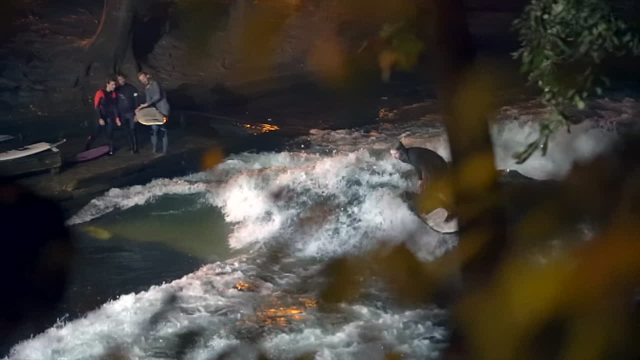 cámara lenta cinematográfica eisbach ola río surfista de vuelta caída comunidad de munich alemania otoño hermosa noche surf de alto flujo agua surf de los alpes de baviera superior flujo pan derecha