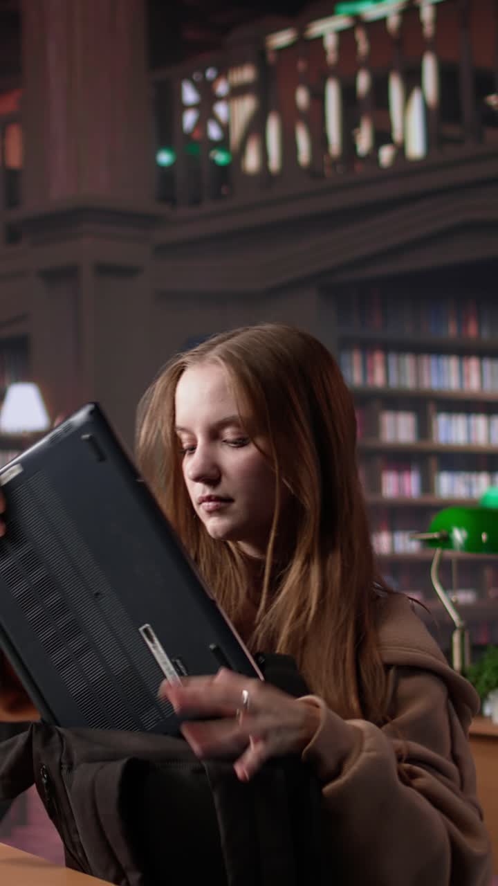 Vertical video focused girl arriving at university library and opening textbook to write notes