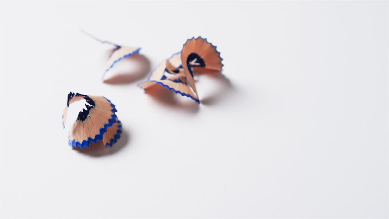 primer plano de virutas de lápiz azul con espacio de copia sobre fondo blanco, en cámara lenta