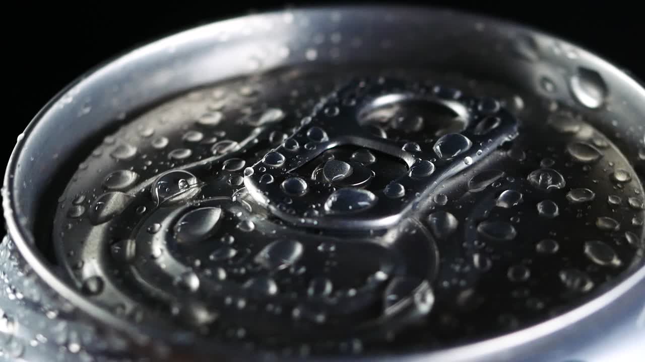 차가운 음료가 검은 바탕에 회전합니다. 소다 또는 맥주 알루미 캔에 물방울이