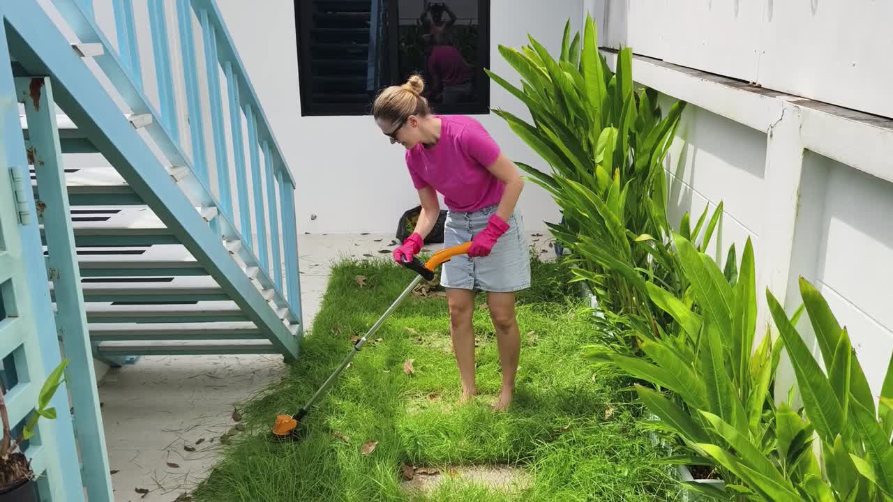 mujer cortando el césped en un jardín del patio trasero