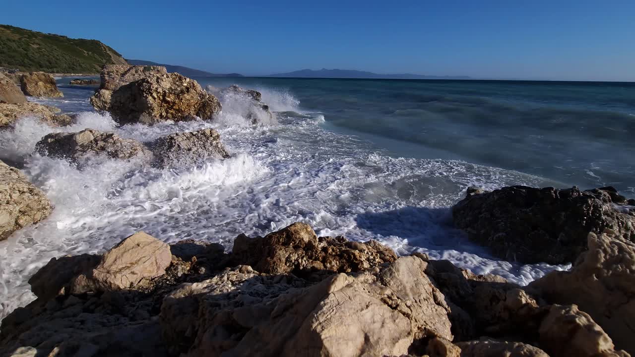 olas marinas salpicando y espumando en acantilados de pie en la playa, hermosa costa en el mediterráneo, albania