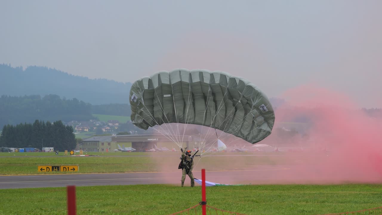 Parachute jumpers landing with smoke at the Airpower event in show with colorful smoke trailing behind a plane, performing aerial maneuvers