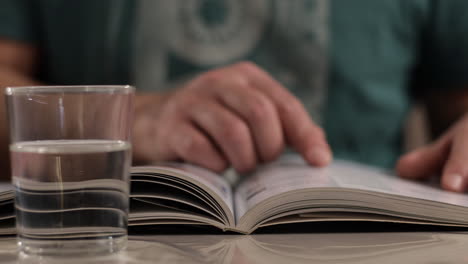 Mano-Masculina-Volteando-Las-Páginas-Del-Libro-Durante-La-Lectura