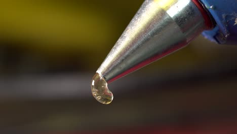 primer plano de la extrusión de pegamento caliente desde la punta metálica de la pistola de pegamento caliente
