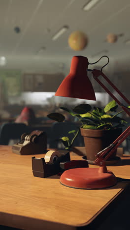 red desk lamp on wooden desk in office setting