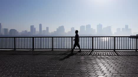 Silhouetten-Eines-10-jährigen-Jungen-Bei-Seinem-Morgenspaziergang-An-Einem-Nebligen-Morgen-Am-Khalid-Lake-In-Sharjah,-Vereinigte-Arabische-Emirate,-4K-Video