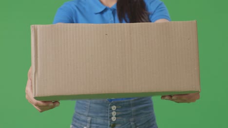 close up of a female courier in blue uniform showing a carton to camera while delivering it on green screen background in the studio