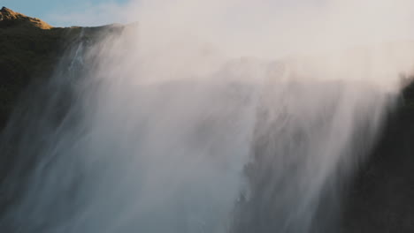 mist from large waterfall cyclone blows over cliff in high winds, iceland