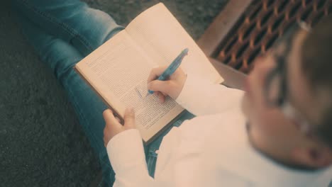 young guy in white shirt and blue jeans draws on book sheet