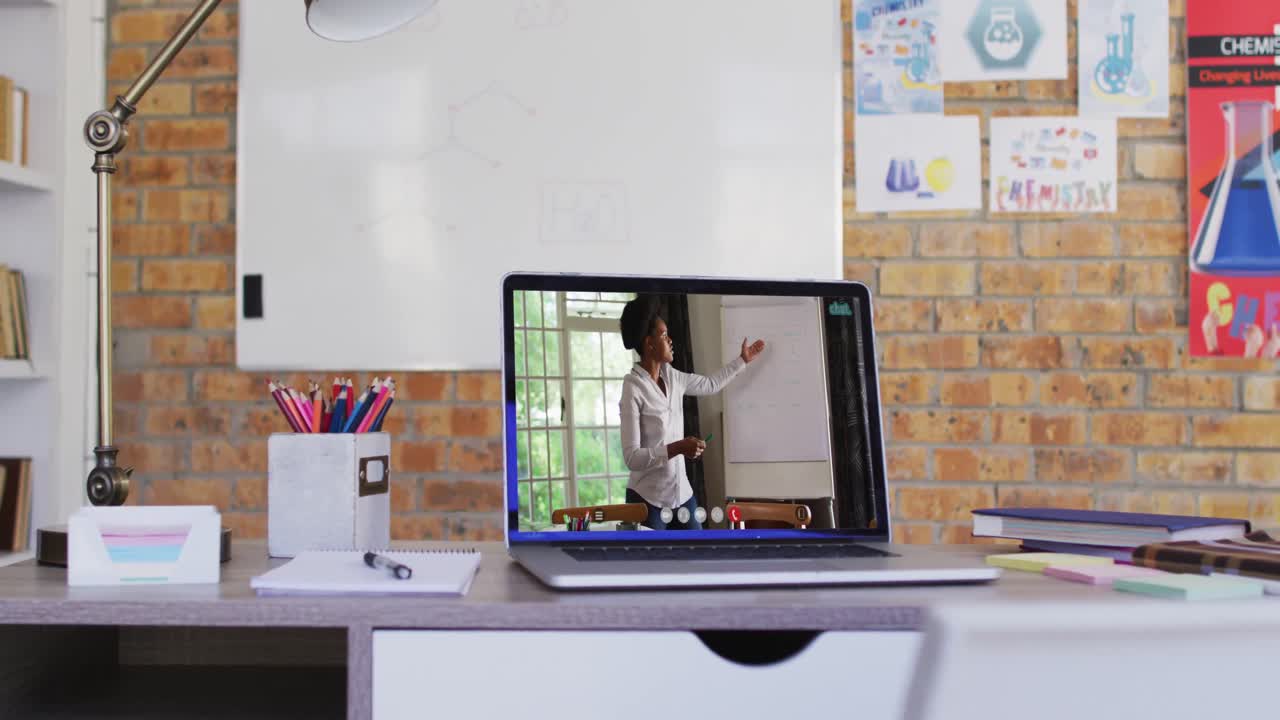 Vista da webcam de professora afro-americana em videochamada no notebook sobre a mesa na escola.