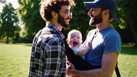 two happy dads with their baby in a park
