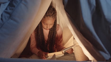 african girl reading book in pillowfort